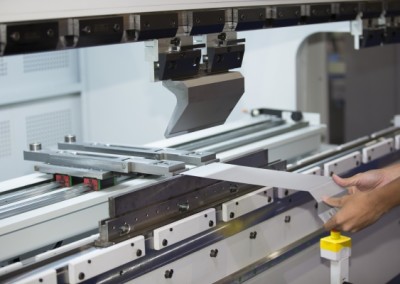 Man holding a piece of sheet metal in a press brake machine Metal Profiling Kent